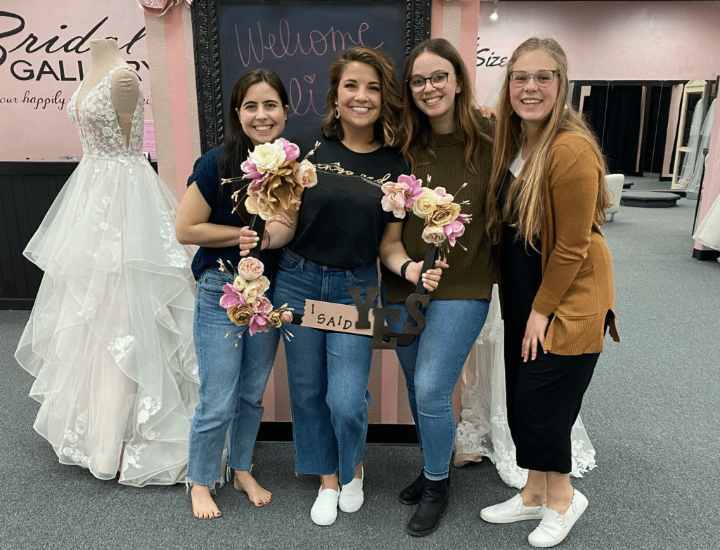 bride and bridesmaids posing with picture frame that says "I said Yes"