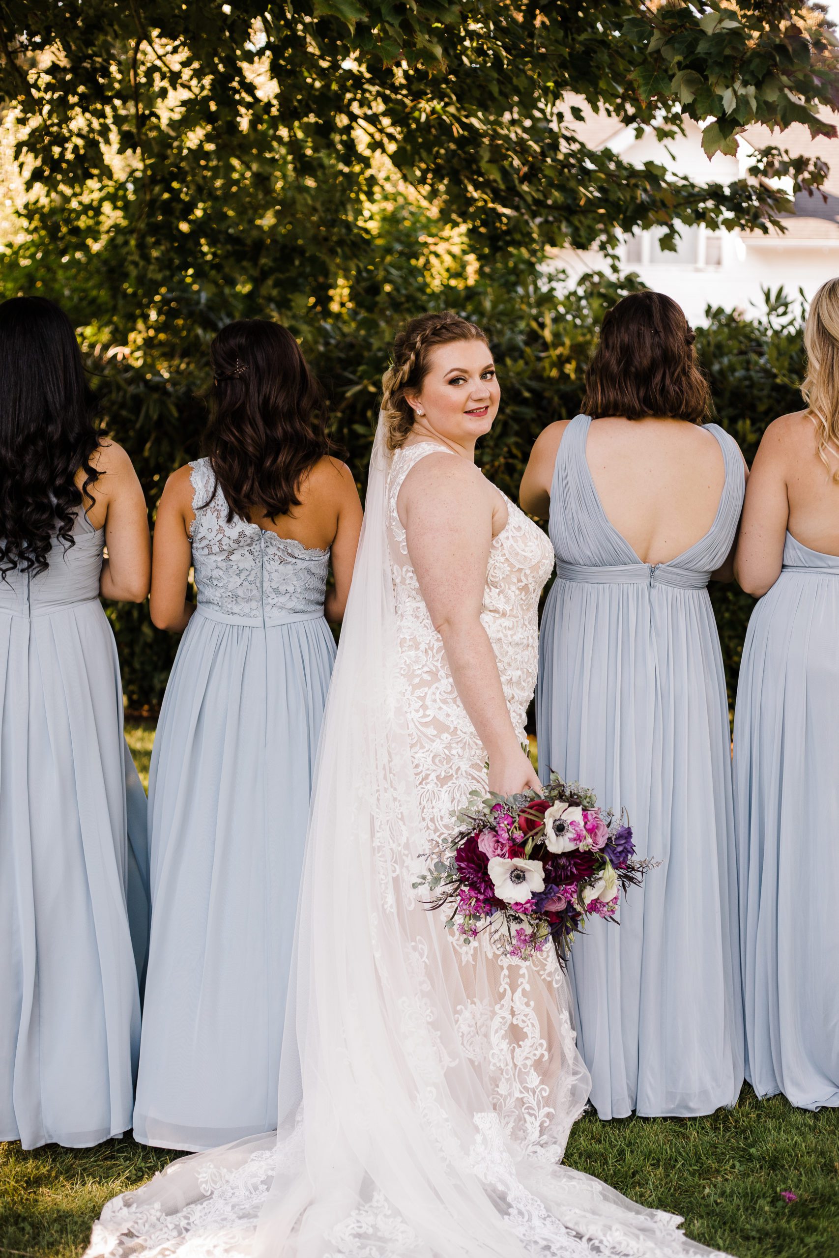 bride looking back while 4 bridesmaids have their backs turned
