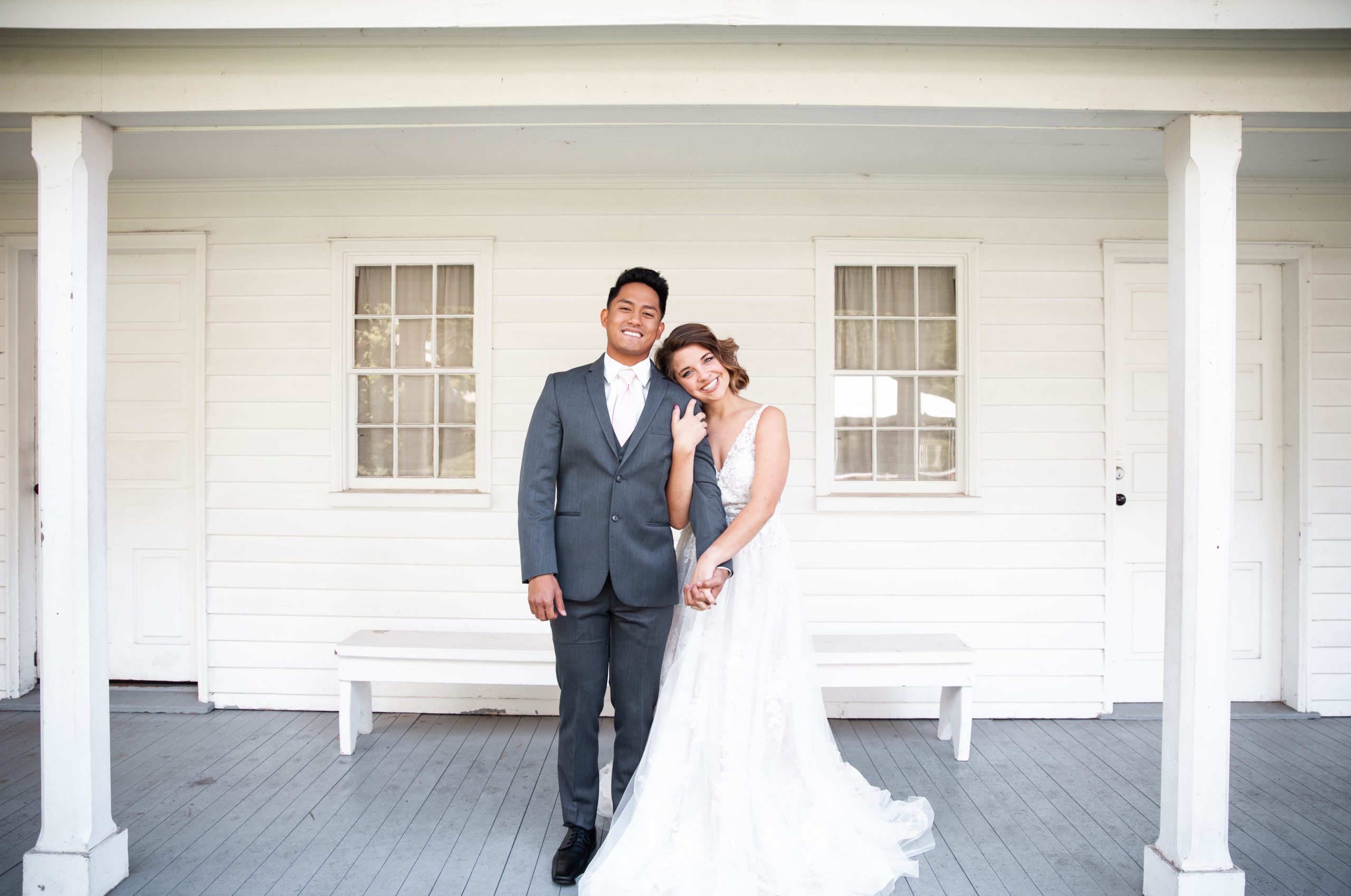 bride and groom in formal wear standing on porch